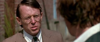 Movie still from “Fire in the Sky” (1993), directed by Robert Lieberman – A person wearing a suit and glasses; Close Up shot, Over the shoulder angle