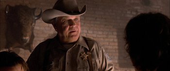 Movie still from “Fire in the Sky” (1993), directed by Robert Lieberman – A man in a sheriff's uniform is looking at the camera; Close Up shot, Low angle