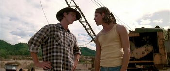 Movie still from “Fire in the Sky” (1993), directed by Robert Lieberman – Two young men are standing next to each other; Medium shot, Low angle