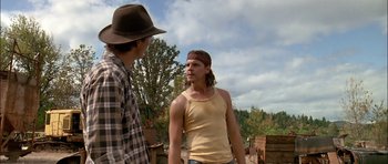 Movie still from “Fire in the Sky” (1993), directed by Robert Lieberman – Two men standing next to each other on a dirt field; Medium shot, Over the shoulder angle