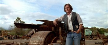 Movie still from “Fire in the Sky” (1993), directed by Robert Lieberman – A man standing in front of an old rusted machine; Medium shot, Low angle