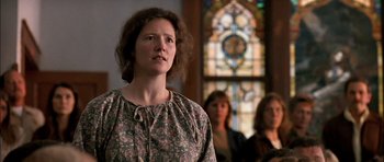 Movie still from “Fire in the Sky” (1993), directed by Robert Lieberman – A woman standing in front of a stained glass window; Close Up shot, Low angle