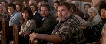 Movie still from “Fire in the Sky” (1993), directed by Robert Lieberman – A man sitting in front of a group of people; Medium shot, High angle
