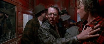 Movie still from “Fire in the Sky” (1993), directed by Robert Lieberman – A group of men standing next to each other in a room; Close Up shot, Over the shoulder angle