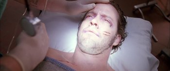 Movie still from “Fire in the Sky” (1993), directed by Robert Lieberman – A man is getting his face waxed by a person; Close Up shot, Overhead angle
