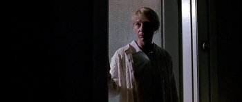 Movie still from “Fire in the Sky” (1993), directed by Robert Lieberman – A man holding a white shirt in front of a window; Close Up shot, Low angle