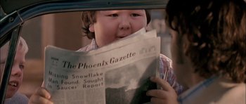 Movie still from “Fire in the Sky” (1993), directed by Robert Lieberman – A young boy reading a newspaper in front of a mirror; Extreme Close Up shot, Over the shoulder angle