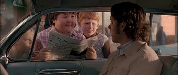 Movie still from “Fire in the Sky” (1993), directed by Robert Lieberman – Two boys are reading a newspaper in the back of a car; Close Up shot, Over the shoulder angle