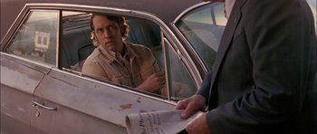 Movie still from “Fire in the Sky” (1993), directed by Robert Lieberman – A man in a car looking at a man in a newspaper; Close Up shot, Over the shoulder angle
