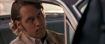 Movie still from “Fire in the Sky” (1993), directed by Robert Lieberman – A man sitting in the back seat of a car looking out the window; Close Up shot, Over the shoulder angle