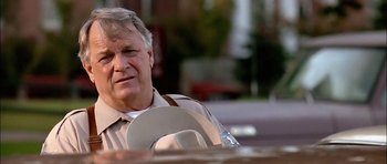 Movie still from “Fire in the Sky” (1993), directed by Robert Lieberman – An older man sitting on a bench in a park; Close Up shot, Low angle