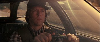 Movie still from “Fire in the Sky” (1993), directed by Robert Lieberman – A man driving a car in the rain with a hat on; Close Up shot, Low angle