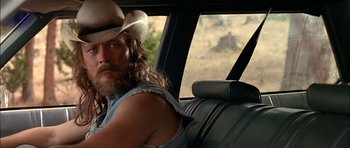 Movie still from “Fire in the Sky” (1993), directed by Robert Lieberman – A man in a cowboy hat sitting in the back seat of a car; Close Up shot, Over the shoulder angle