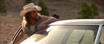 Movie still from “Fire in the Sky” (1993), directed by Robert Lieberman – A man in a cowboy hat leaning on the hood of a car; Medium shot, Over the shoulder angle