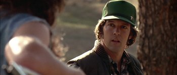 Movie still from “Fire in the Sky” (1993), directed by Robert Lieberman – A young man wearing a green hat and a plaid shirt; Close Up shot, Over the shoulder angle
