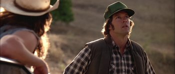 Movie still from “Fire in the Sky” (1993), directed by Robert Lieberman – A man wearing a green hat standing next to a deer; Close Up shot, Low angle
