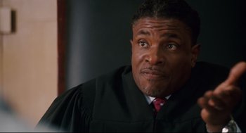 Movie still from “First Sunday” (2008), directed by David E. Talbert – A man wearing a black robe and a red tie; Close Up shot, Low angle