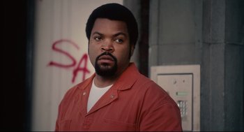 Movie still from “First Sunday” (2008), directed by David E. Talbert – Ice cube in a red shirt in front of a red wall; Close Up shot, Over the shoulder angle