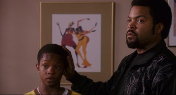 Movie still from “First Sunday” (2008), directed by David E. Talbert – A man and a young boy standing next to each other in a room; Close Up shot, Over the shoulder angle