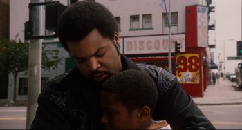 Movie still from “First Sunday” (2008), directed by David E. Talbert – A man and a boy are hugging in a city; Close Up shot, Over the shoulder angle