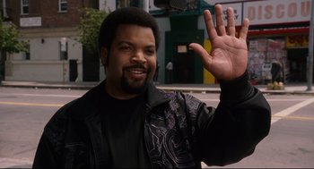 Movie still from “First Sunday” (2008), directed by David E. Talbert – A man waving at the camera while holding his hand up; Medium shot, Over the shoulder angle