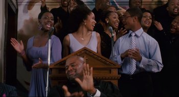 Movie still from “First Sunday” (2008), directed by David E. Talbert – A group of people standing in front of microphones and microphones; Medium shot, Low angle