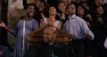Movie still from “First Sunday” (2008), directed by David E. Talbert – A group of people singing in front of a microphone; Medium shot, Low angle