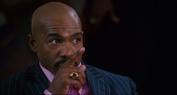 Movie still from “First Sunday” (2008), directed by David E. Talbert – A man in a suit and tie with his finger to his lips; Close Up shot, Low angle