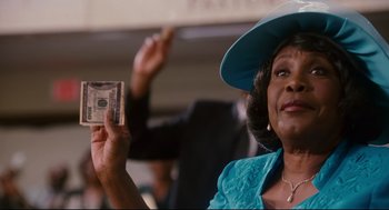 Movie still from “First Sunday” (2008), directed by David E. Talbert – An older woman in a blue hat holding a $ 1 0 0 bill; Close Up shot, Low angle
