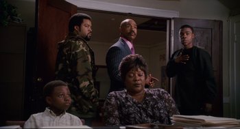 Movie still from “First Sunday” (2008), directed by David E. Talbert – A group of people standing around a table; Medium shot, Over the shoulder angle