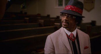 Movie still from “First Sunday” (2008), directed by David E. Talbert – A man wearing a suit and a hat in front of a room; Close Up shot, Over the shoulder angle