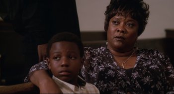 Movie still from “First Sunday” (2008), directed by David E. Talbert – A woman and a boy sitting next to each other in a room; Close Up shot, Over the shoulder angle