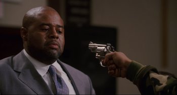 Movie still from “First Sunday” (2008), directed by David E. Talbert – A man in a suit and tie holding a gun up to a man's face; Close Up shot, Over the shoulder angle