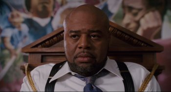 Movie still from “First Sunday” (2008), directed by David E. Talbert – A bald man wearing a white shirt and blue tie; Close Up shot, Low angle