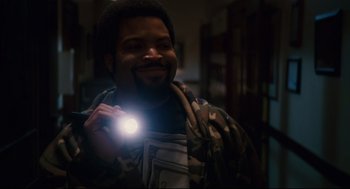 Movie still from “First Sunday” (2008), directed by David E. Talbert – A man holding a flashlight in a dark room; Medium shot, High angle