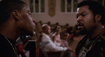Movie still from “First Sunday” (2008), directed by David E. Talbert – Two men are sitting in a church and one of them is talking to another man; Close Up shot, Over the shoulder angle