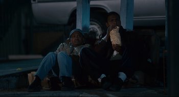 Movie still from “First Sunday” (2008), directed by David E. Talbert – A couple of men sitting next to each other on some steps; Medium shot, High angle
