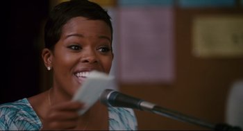Movie still from “First Sunday” (2008), directed by David E. Talbert – A woman holding a microphone and a piece of paper in front of her mouth; Close Up shot, Low angle