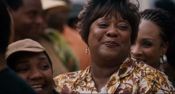 Movie still from “First Sunday” (2008), directed by David E. Talbert – An older woman is smiling while standing in a crowd of people; Close Up shot, Low angle