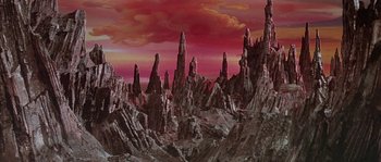 Movie still from “Flash Gordon” (1980), directed by Mike Hodges – A painting of a red sky and a mountain range; Extreme Wide shot, High angle