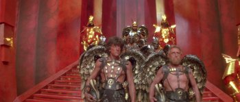 Movie still from “Flash Gordon” (1980), directed by Mike Hodges – A group of men dressed in gold and black costumes; Wide shot, Low angle