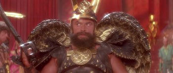 Movie still from “Flash Gordon” (1980), directed by Mike Hodges – A bearded man in a gold and black costume; Close Up shot, Low angle