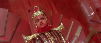 Movie still from “Flash Gordon” (1980), directed by Mike Hodges – A person wearing a gold and red costume; Close Up shot, High angle