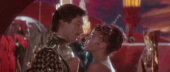 Movie still from “Flash Gordon” (1980), directed by Mike Hodges – A man and a woman are kissing each other in front of a crowd of onlookers; Close Up shot, Over the shoulder angle