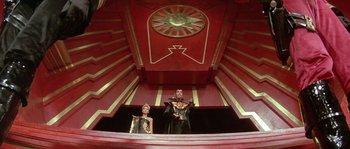 Movie still from “Flash Gordon” (1980), directed by Mike Hodges – A couple of people that are standing in a room; Wide shot, Low angle