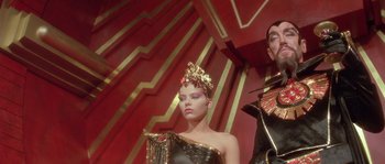 Movie still from “Flash Gordon” (1980), directed by Mike Hodges – A woman in a black dress and a man in a black and red suit; Medium shot, Low angle