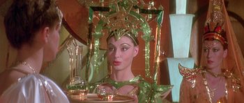 Movie still from “Flash Gordon” (1980), directed by Mike Hodges – A woman in a green costume holding a tray of food; Medium shot, Low angle