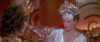 Movie still from “Flash Gordon” (1980), directed by Mike Hodges – A woman in a silver costume holding a glass of wine; Close Up shot, Over the shoulder angle