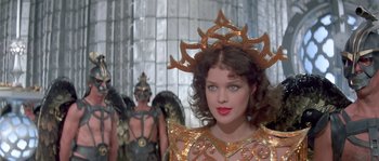 Movie still from “Flash Gordon” (1980), directed by Mike Hodges – A woman in a gold costume with other people in the background; Close Up shot, Over the shoulder angle