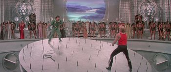 Movie still from “Flash Gordon” (1980), directed by Mike Hodges – A group of people standing in front of an audience; Wide shot, High angle